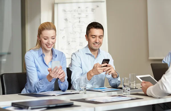 Lächelnde Geschäftsleute mit Smartphones im Büro — Stockfoto