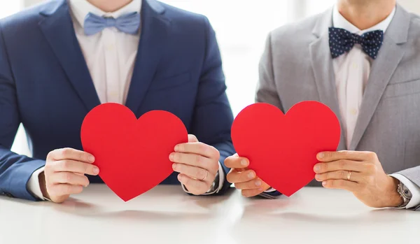 Zblízka mužské homosexuální pár drží červená srdce — Stock fotografie