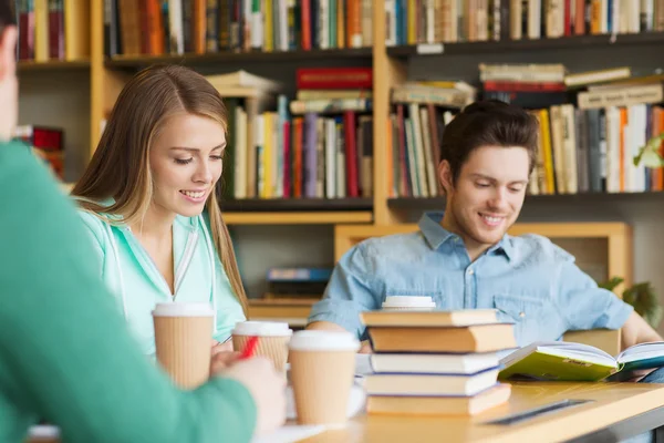 Estudiantes leyendo y tomando café en la biblioteca — Foto de Stock