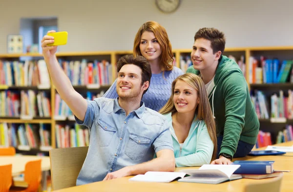 Estudiantes con smartphone tomando selfie en la biblioteca — Foto de Stock