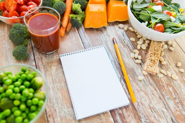 Gros plan des légumes mûrs et cahier sur la table — Photo