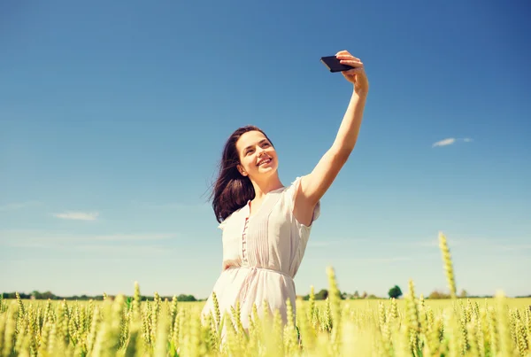 Smiling girl with smartphone on cereal field — Stock Photo, Image
