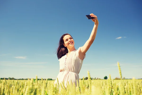 Leende flicka med smartphone på spannmål fältet — Stockfoto