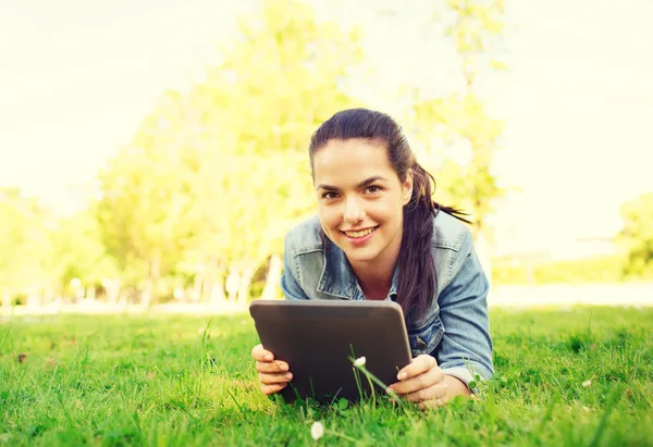 S úsměvem mladá dívka tablet pc ležet na trávě — Stock fotografie