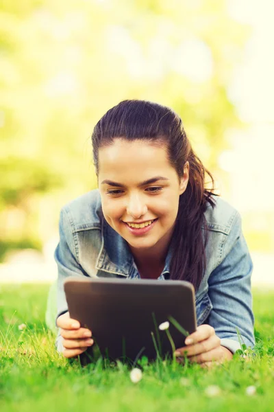 Sonriente chica joven tableta pc acostado en la hierba —  Fotos de Stock