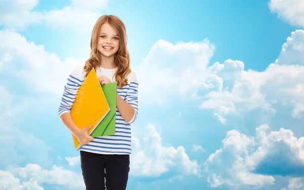 Menina feliz segurando pastas coloridas sobre o céu azul — Fotografia de Stock