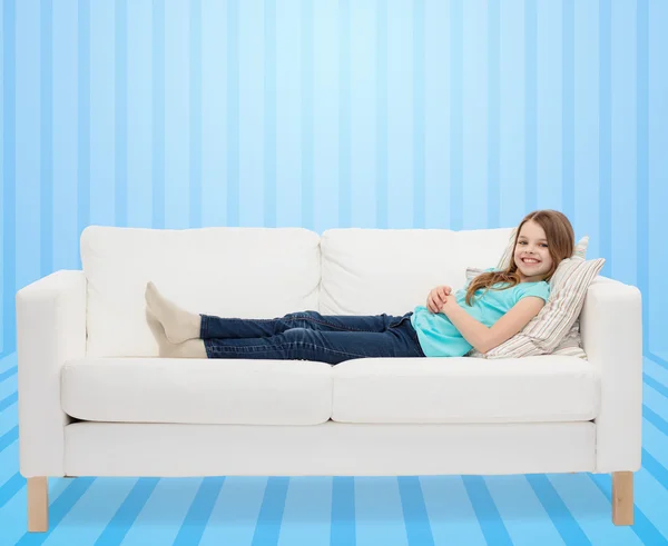 Smiling little girl lying on sofa — Stock Photo, Image