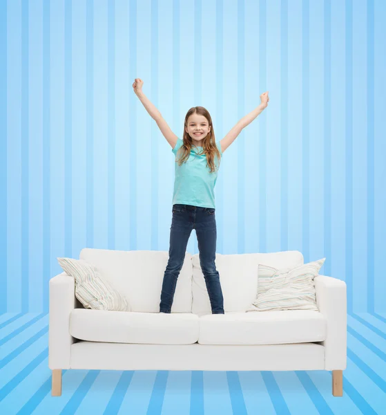 Улыбающаяся маленькая девочка, прыгающая на диване — стоковое фото