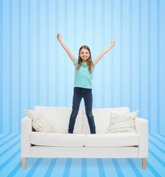 Smiling little girl jumping on sofa — Stock Photo, Image