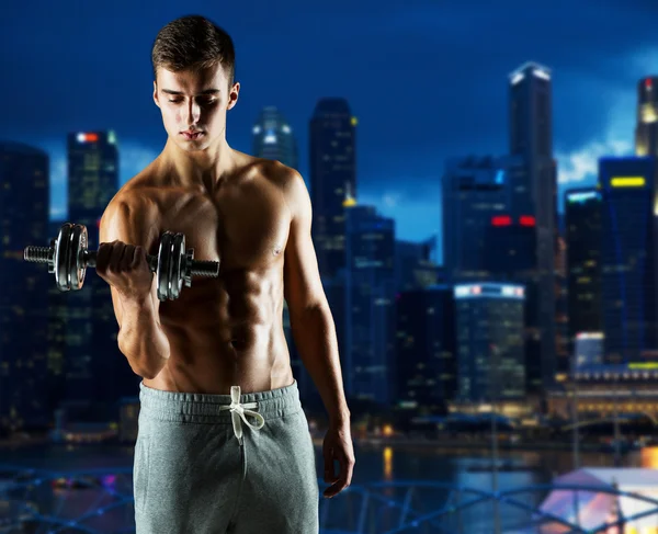 Young man with dumbbell flexing biceps — Stock Photo, Image