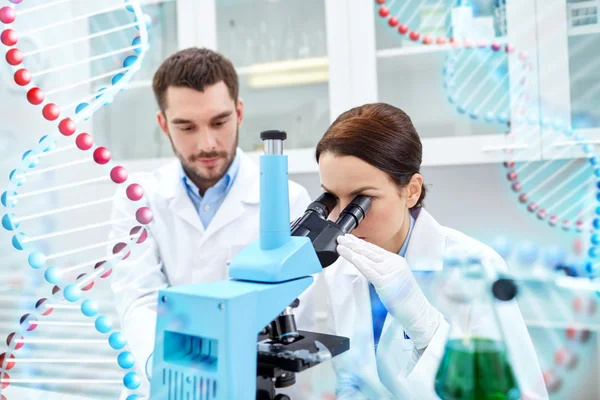 Científicos con microscopio haciendo pruebas en laboratorio —  Fotos de Stock