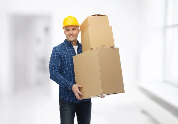 Smiling man in helmet with cardboard boxes — Stock Photo, Image