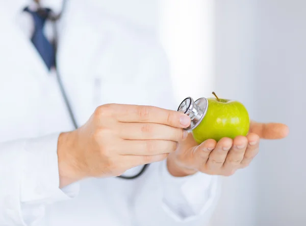 Manliga läkare med grönt äpple och stetoskop — Stockfoto