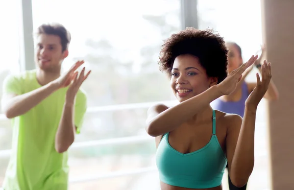 Groupe de personnes souriantes dansant en salle de gym ou studio — Photo