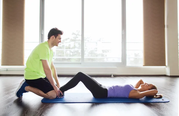 Kvinna med personlig tränare gör sit ups i gym — Stockfoto