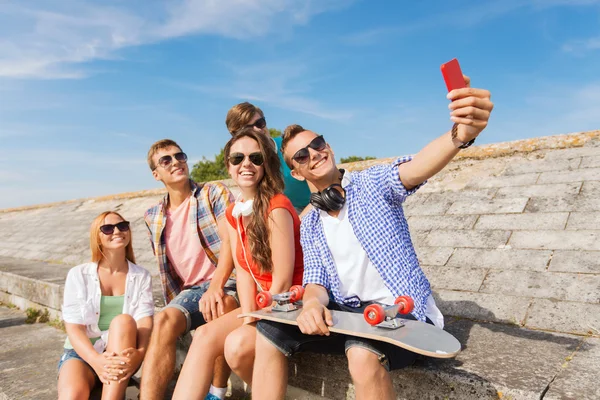 Grupo de amigos sorridentes com smartphone ao ar livre — Fotografia de Stock