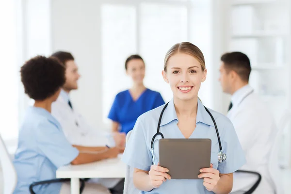 Medico felice con tablet pc sopra il team in clinica — Foto Stock