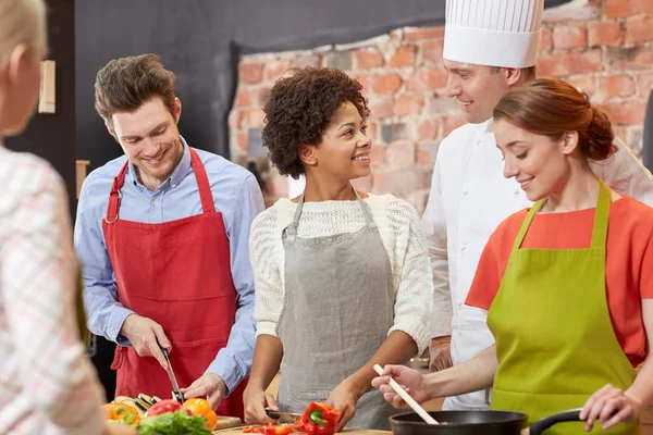 Glada vänner och kocken laga mat i köket — Stockfoto