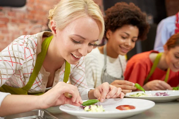 Mulheres felizes cozinhar e decorar pratos — Fotografia de Stock