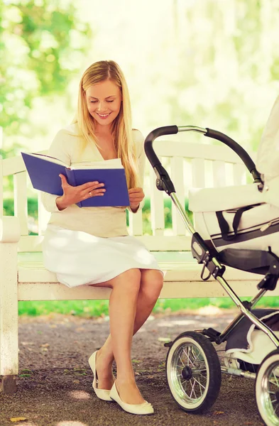 Glad mamma med bok och barnvagn i park — Stockfoto