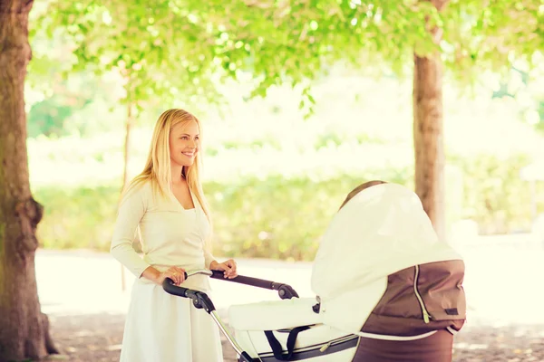 Glad mamma med barnvagn i park — Stockfoto