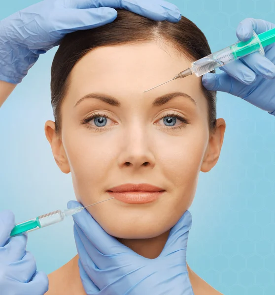 Woman face and surgeon hands with syringes — Stock Photo, Image