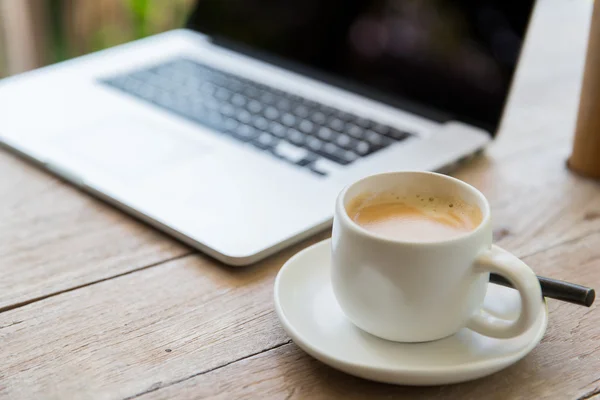 Primo piano del computer portatile e della tazza di caffè sul tavolo dell'ufficio — Foto Stock