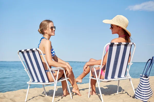 Mulheres felizes banhos de sol em lounges na praia — Fotografia de Stock