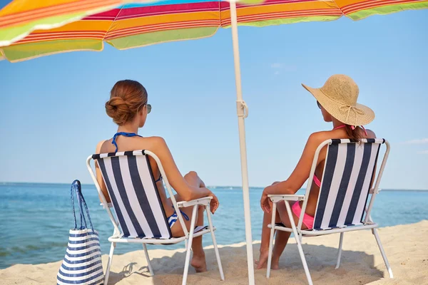 Szczęśliwe kobiety opalanie w salonach na plaży — Zdjęcie stockowe