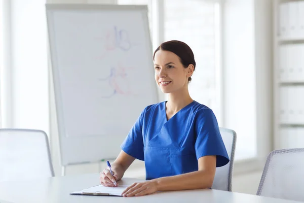 Feliz doctora o enfermera escribiendo al portapapeles —  Fotos de Stock