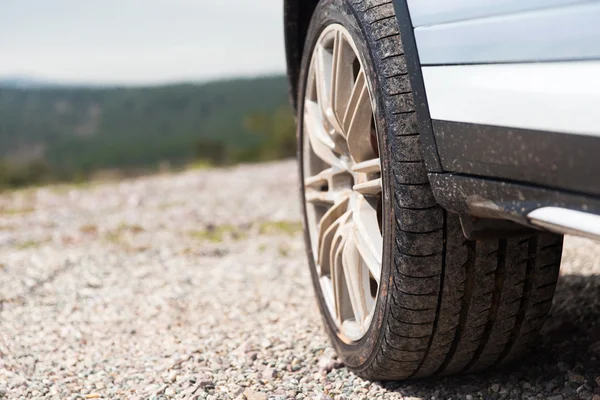 Närbild av smutsig bil rullar på klippa — Stockfoto