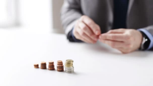 Close up of businessman putting coins into columns — Stock Video