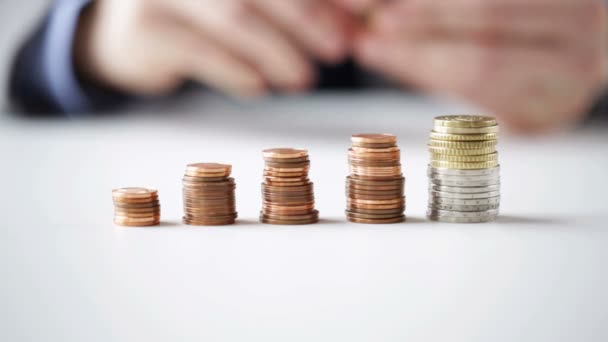 Close up of businessman putting coins into columns — Stock Video