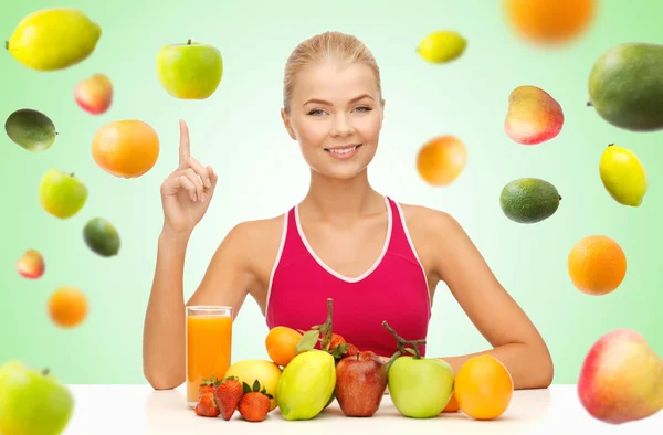 Woman with juice and fruits pointing finger up — Stock Photo, Image