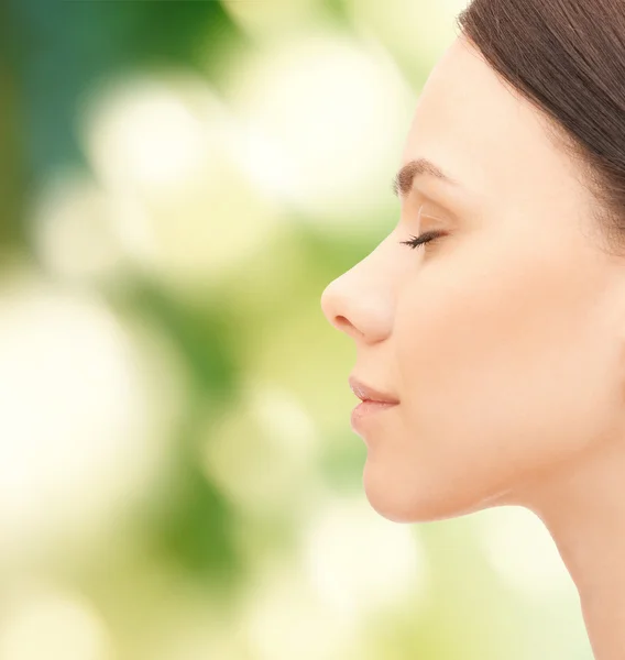 Mooie jonge vrouw gezicht op groene achtergrond — Stockfoto