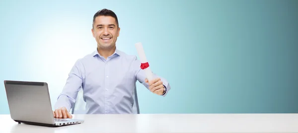 Homme souriant avec diplôme et ordinateur portable à la table — Photo