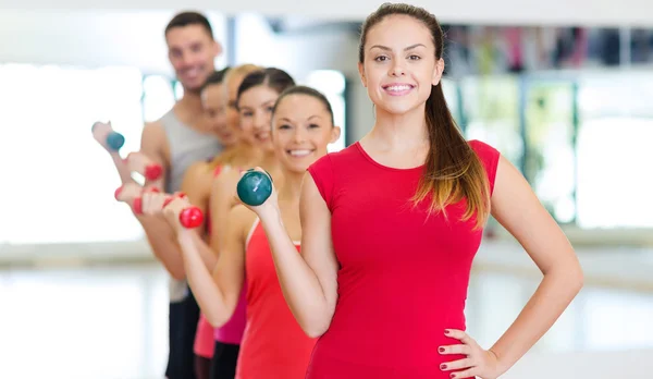 Groupe de personnes souriantes avec haltères dans la salle de gym — Photo