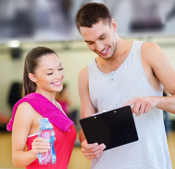 Allenatore maschio sorridente con donna in palestra — Foto Stock