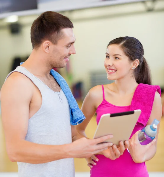 Dos personas sonrientes con tablet PC en el gimnasio —  Fotos de Stock