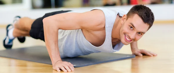 Smiling man doing push-ups in the gym — Stock Photo, Image