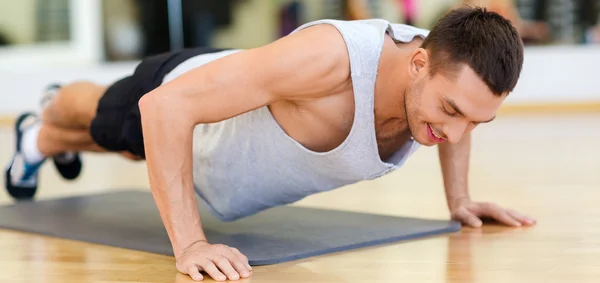 Hombre sonriente haciendo flexiones en el gimnasio — Foto de Stock