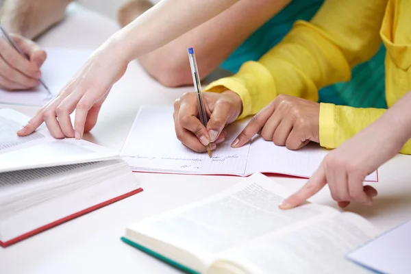 Primer plano de las manos de los estudiantes escribiendo a los cuadernos —  Fotos de Stock