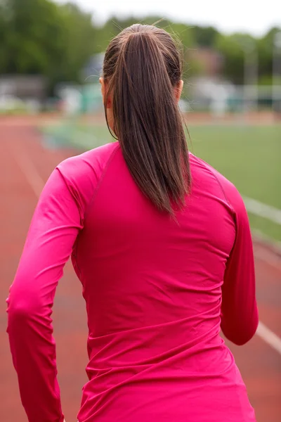 Woman running on track outdoors from back — Stock Photo, Image