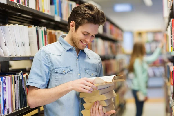 Gelukkig student of man met boek in bibliotheek — Stockfoto