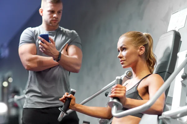 Hombres y mujeres flexionando los músculos en la máquina de gimnasio — Foto de Stock