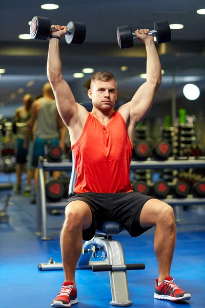 Jonge man met halters buigen spieren in de sportschool — Stockfoto