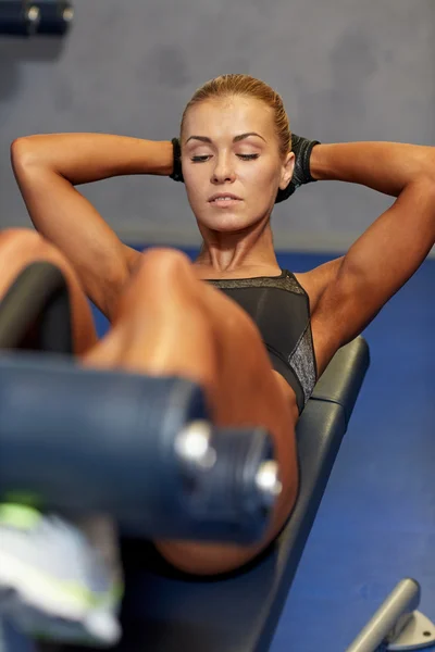 Kvinnan spänna magmusklerna på bänk i gym — Stockfoto