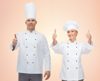 happy chefs or cooks couple showing thumbs up clipart