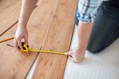 close up of male hands measuring flooring clipart