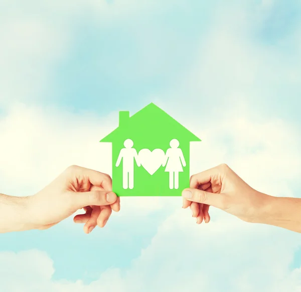 Hands holding green house with family — Stock Photo, Image